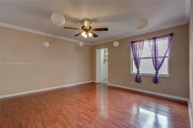 empty room featuring a ceiling fan, baseboards, crown molding, and wood finished floors