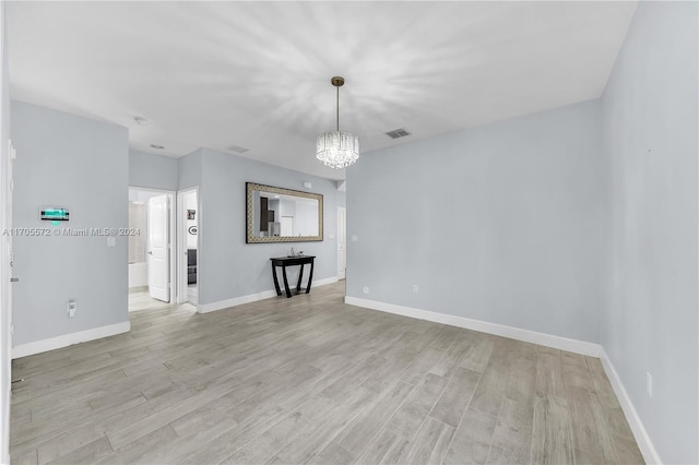 empty room featuring light hardwood / wood-style floors and a notable chandelier