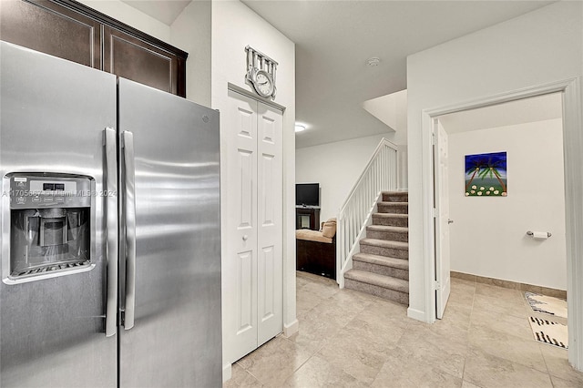 kitchen featuring stainless steel fridge, light tile patterned floors, and dark brown cabinets