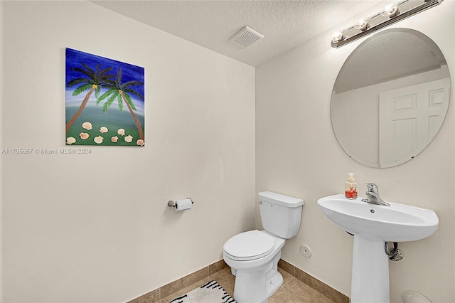 bathroom featuring tile patterned flooring, a textured ceiling, and toilet