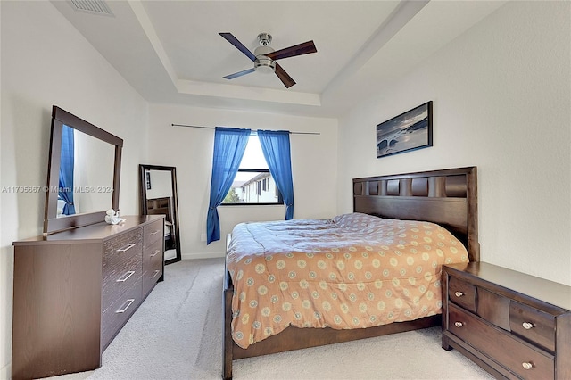 bedroom featuring a tray ceiling, ceiling fan, and light colored carpet