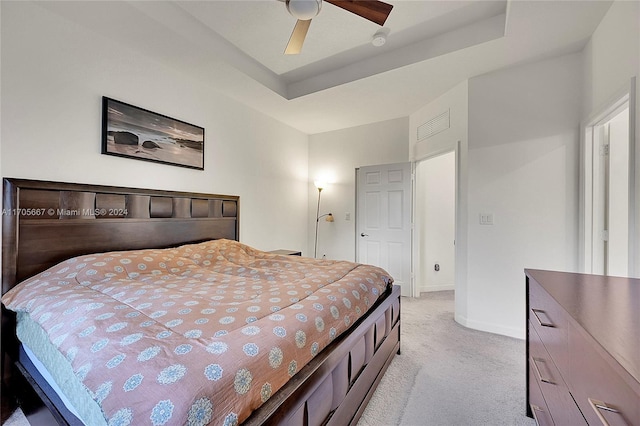 bedroom with light colored carpet, ceiling fan, and a tray ceiling