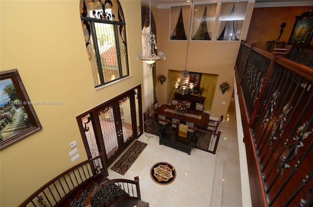 staircase with tile patterned floors, french doors, a high ceiling, and an inviting chandelier