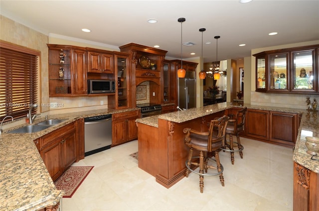 kitchen featuring light stone counters, sink, stainless steel appliances, and decorative light fixtures