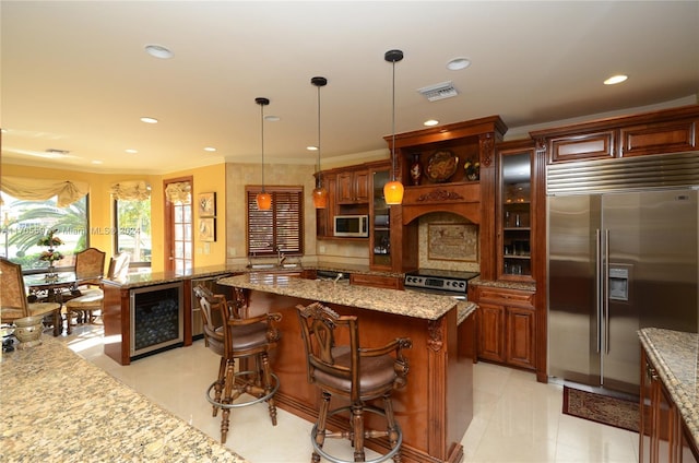 kitchen with kitchen peninsula, a breakfast bar, beverage cooler, built in appliances, and decorative light fixtures