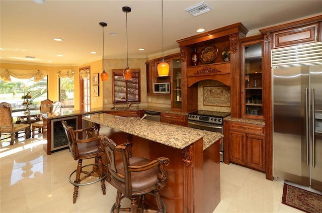 kitchen featuring a kitchen breakfast bar, wine cooler, light stone counters, built in appliances, and pendant lighting