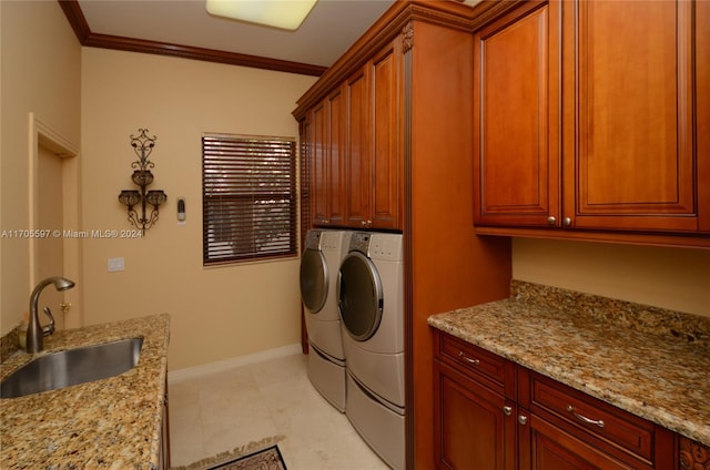 clothes washing area featuring crown molding, cabinets, separate washer and dryer, and sink