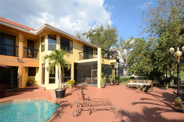 back of house featuring a sunroom, a patio area, an outdoor hangout area, and a balcony