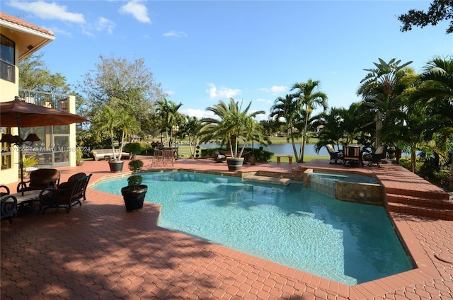 view of pool featuring an in ground hot tub, a water view, and a patio