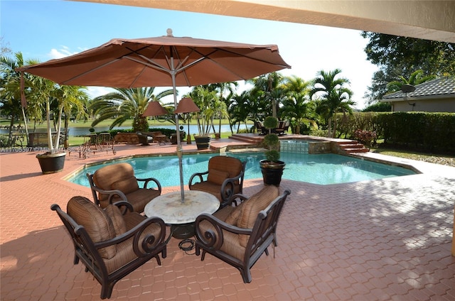 view of pool with a patio area, a water view, and an in ground hot tub