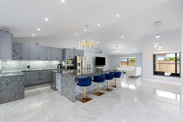 kitchen featuring gray cabinetry, a large island, stainless steel appliances, dark stone countertops, and pendant lighting