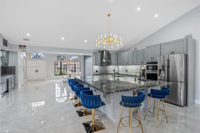 kitchen with a kitchen breakfast bar, sink, wall chimney exhaust hood, and stainless steel appliances