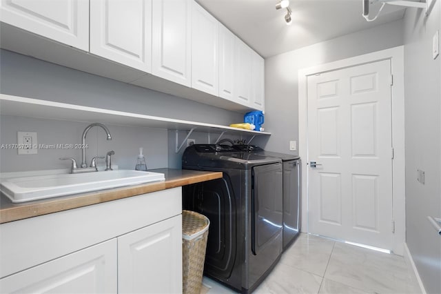 clothes washing area featuring washing machine and clothes dryer, cabinets, and sink