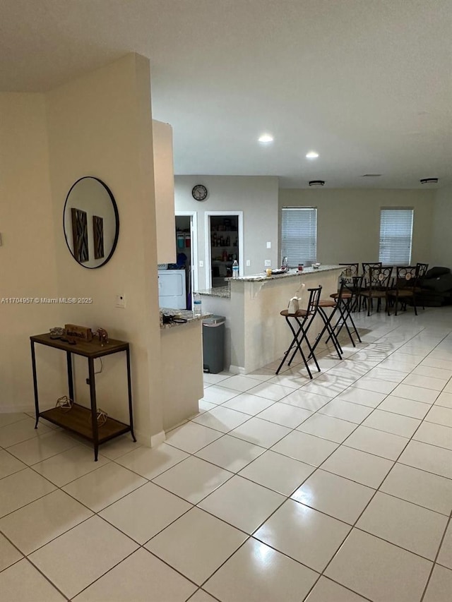 kitchen featuring a kitchen breakfast bar, kitchen peninsula, and light tile patterned floors