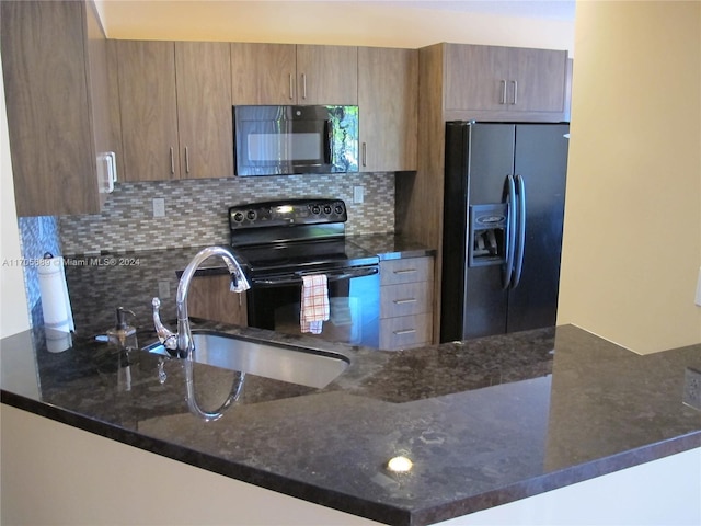 kitchen with sink, tasteful backsplash, kitchen peninsula, dark stone counters, and black appliances