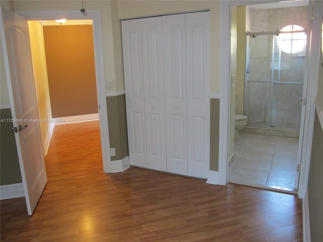 unfurnished bedroom featuring connected bathroom, a closet, and hardwood / wood-style flooring