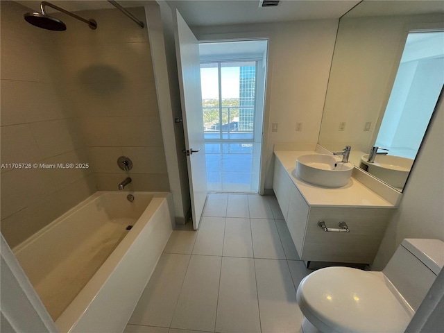 full bathroom featuring tile patterned flooring, vanity, tiled shower / bath combo, and toilet