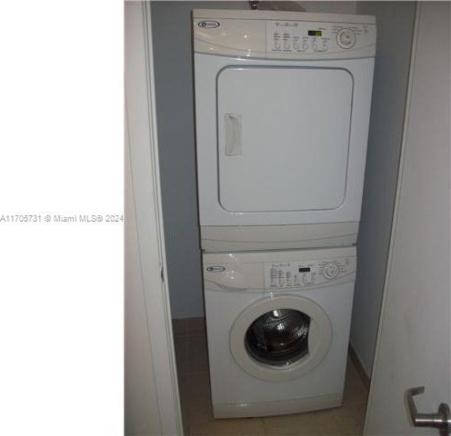 clothes washing area featuring light tile patterned floors and stacked washer and dryer