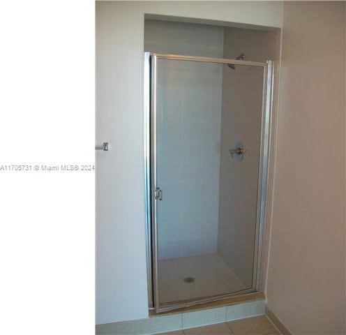 bathroom with tile patterned flooring and walk in shower