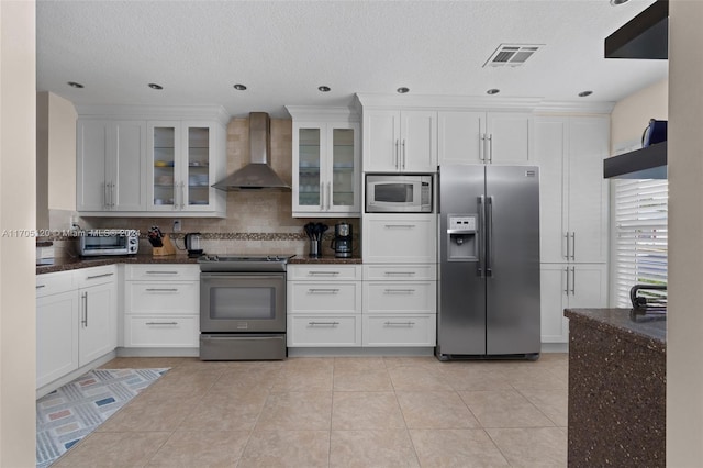 kitchen with backsplash, stainless steel appliances, white cabinetry, and wall chimney range hood