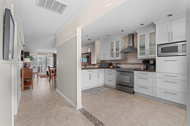 kitchen featuring white cabinetry, wall chimney range hood, stainless steel appliances, and ornamental molding