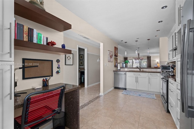 kitchen featuring kitchen peninsula, stainless steel appliances, sink, white cabinetry, and hanging light fixtures