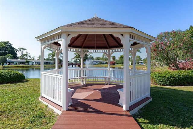 wooden terrace featuring a gazebo, a water view, and a lawn