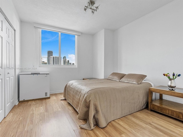 bedroom with a closet, light hardwood / wood-style flooring, and a textured ceiling