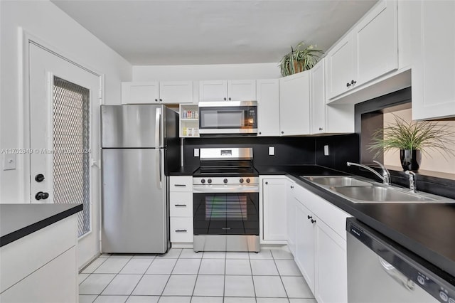 kitchen featuring appliances with stainless steel finishes, light tile patterned floors, white cabinetry, and sink