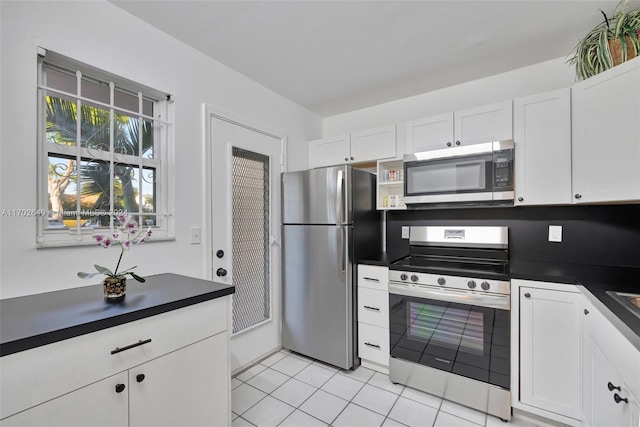 kitchen with light tile patterned flooring, white cabinets, and stainless steel appliances