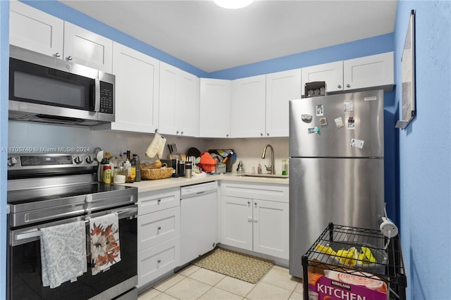 kitchen with light tile patterned floors, stainless steel appliances, white cabinetry, and sink