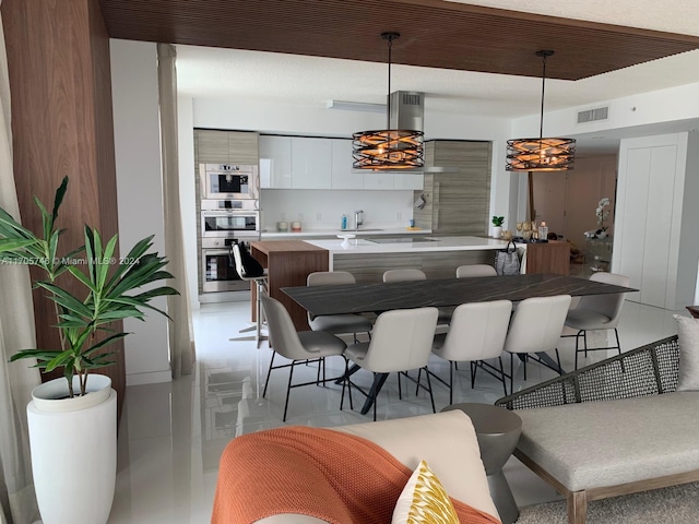 kitchen with black electric stovetop, kitchen peninsula, double oven, decorative light fixtures, and white cabinetry