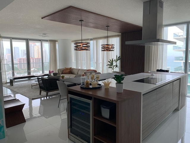 kitchen with hanging light fixtures, beverage cooler, a textured ceiling, black electric cooktop, and island range hood