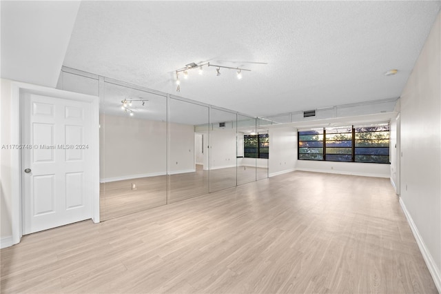 unfurnished room with a textured ceiling and light hardwood / wood-style floors