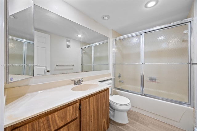 full bathroom with toilet, vanity, bath / shower combo with glass door, and hardwood / wood-style flooring