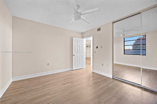 unfurnished bedroom with light wood-type flooring, a textured ceiling, a closet, and ceiling fan