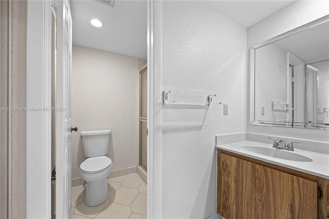 bathroom with tile patterned flooring, vanity, toilet, and a shower with door