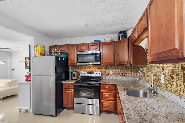 kitchen featuring light stone countertops, sink, light tile patterned floors, and stainless steel appliances