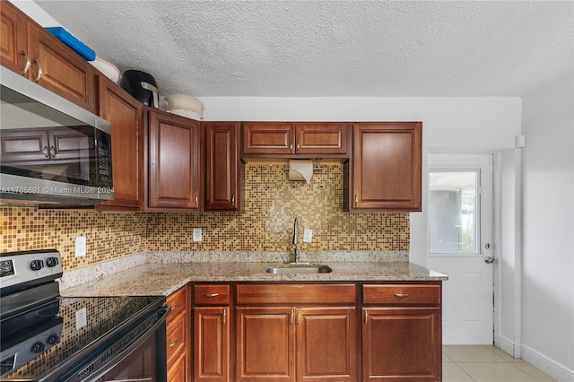 kitchen with light stone countertops, light tile patterned floors, stainless steel appliances, and sink