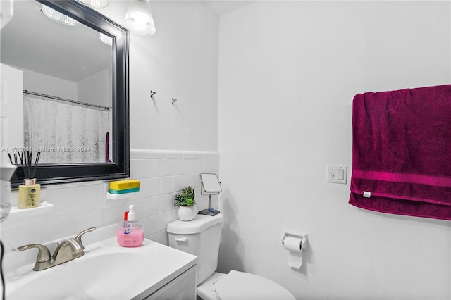 bathroom with vanity, toilet, and tile walls