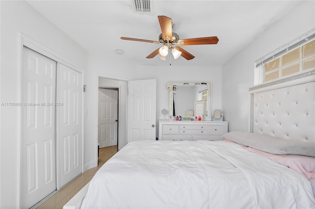 tiled bedroom with ceiling fan and a closet