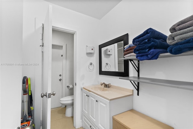 bathroom with toilet, vanity, and tile patterned floors