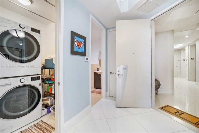 laundry area featuring light tile patterned flooring and stacked washer and dryer