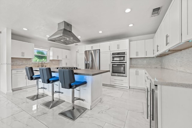 kitchen with white cabinetry, a center island, island range hood, a breakfast bar, and appliances with stainless steel finishes