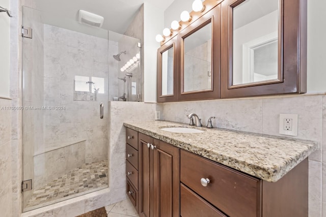 bathroom with vanity, an enclosed shower, decorative backsplash, and tile walls