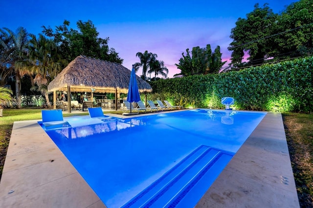 pool at dusk with a gazebo and a patio area