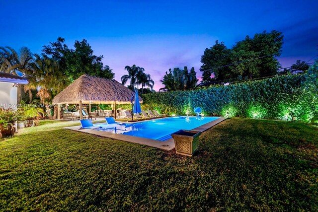 pool at dusk featuring a gazebo and a yard