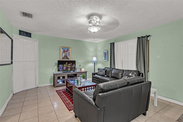 living room featuring ceiling fan, light tile patterned floors, and a textured ceiling