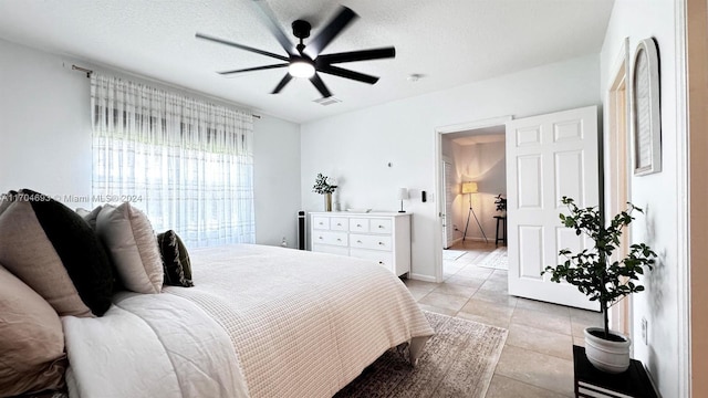 tiled bedroom featuring ceiling fan and a textured ceiling