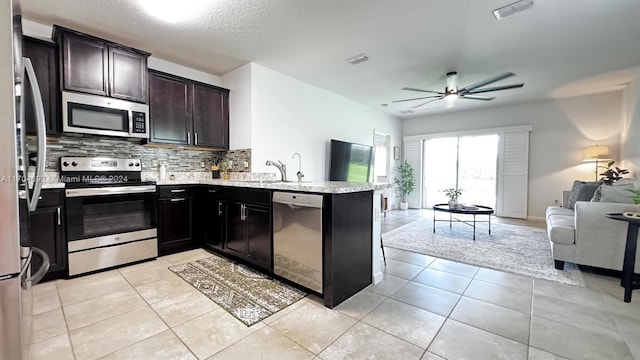 kitchen featuring decorative backsplash, ceiling fan, light tile patterned floors, appliances with stainless steel finishes, and kitchen peninsula